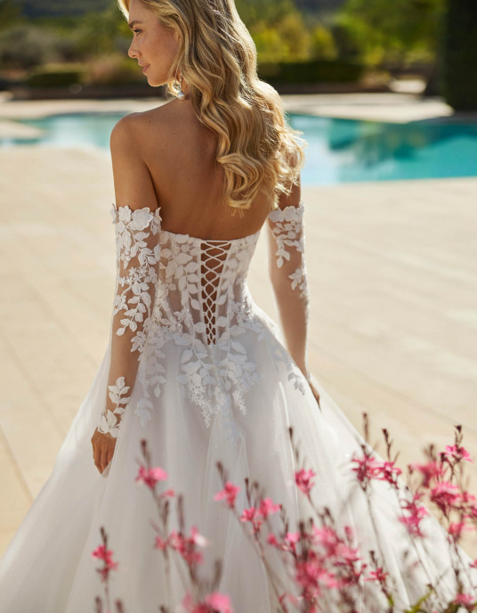 Robes de mariées  ADRIANA ALIER SIMONA est une Robe de mariée longue volumineuse en tulle avec bustier en dentelle, perles, encolure bustier, manches amovibles et dos corset. 