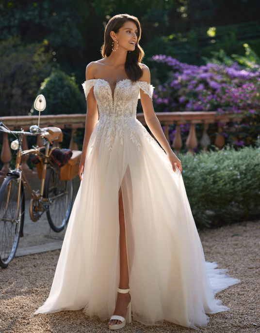 Robes de mariées   Delphe Robe de mariée romantique de style fourreau confectionnée en tulle, dentelle et perles. Modèle doté d'un décolleté plongeant, de bretelles amovibles et d'une jupe fendue sur le côté. 