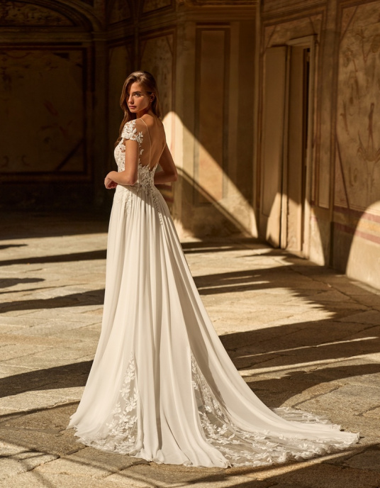 Robes de mariées  ALBERTO PALATCHI ADELE Robe de mariée trapèze de style romantique. Elle présente un corsage structuré en dentelle et perles, avec un décolleté illusion, sur une jupe en mousseline fendue sur le côté et ornée de délicates applications de dentelle. 