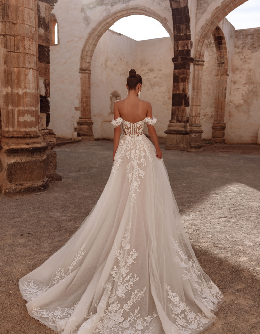 Robes de mariées  Nicole Couture Ariella allie glamour et romance moderne. Son corset structuré et ses manches délicates soulignent la silhouette, tandis que la jupe en tulle léger flotte avec élégance. Les appliqués de dentelle ajoutent raffinement et profondeur.  