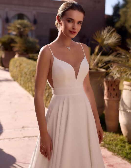 Robes de mariées  Bianco Evento Luca Robe de mariée trapèze, confectionnée dans un crêpe de laine haut de gamme, ornée d’une longue traîne et sublimée par un dos ouvert ainsi qu’un décolleté en V. 