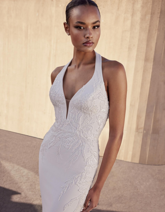 Robes de mariées  Pronovias BREBI : Robe sirène élégante à col halter, alliant glamour et sensualité. Confectionnée en crêpe, dentelle et ornée de perles, cette robe est parfaite pour une mariée raffinée souhaitant se démarquer lors de son mariage 