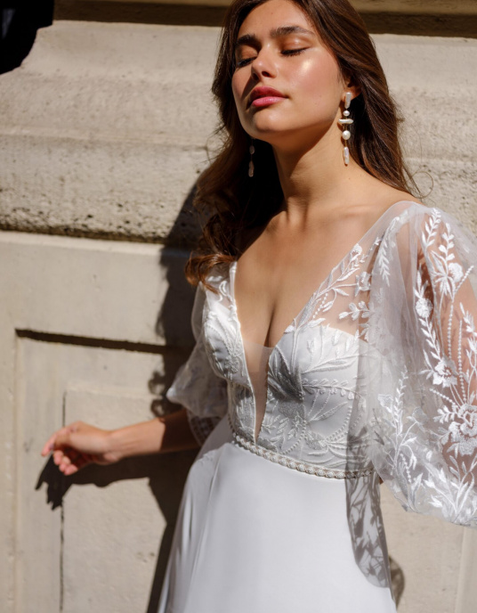 Robes de mariées  Lambert Creation Céleste Allure fluide et légère pour cette robe en mousseline fendue devant, son joli buste à manches bouffantes en tulle brodé fleurs. 