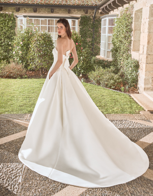 Robes de mariées  ALBERTO PALATCHI CHIAKI Robe de coupe princesse avec encolure sans bretelles, fabriquée en mikado ida. Détails en strass sur l’encolure et le laçage arrière. 