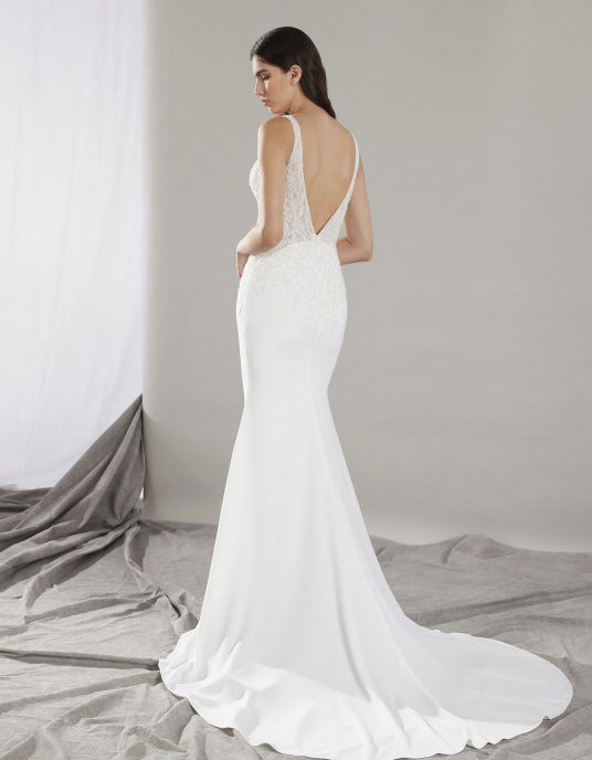 Robes de mariées  Pronovias CLIN coupe sirène est une ode à votre silhouette, avec son corsage décolleté en V et ses bretelles brodées. La dentelle brodée de paillettes orne votre taille avec une subtile transparence. Le dos nu présente un décolleté en V plongeant. 