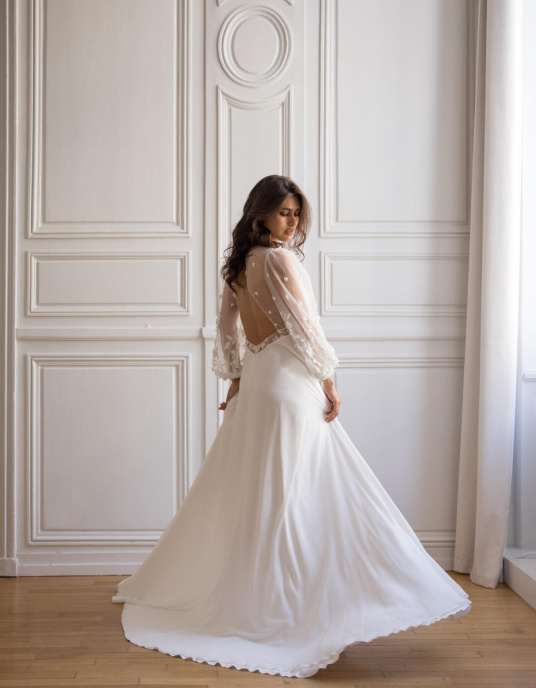 Robes de mariées  Lambert Creation Hélia Robe fendue et boutonnée devant, fluide et originale avec sa ceinture et ses manches longues bouffantes en tulle brodé. 