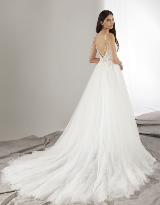 Robes de mariées  Pronovias HERO-Le corsage, décolleté en V avec des bretelles ornées de bijoux et confectionné en dentelle très fine brodée de paillettes, glisse sur la jupe en tulle dans un jeu de transparences. 