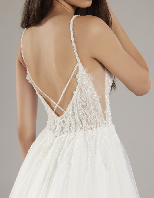 Robes de mariées  Pronovias HERO-Le corsage, décolleté en V avec des bretelles ornées de bijoux et confectionné en dentelle très fine brodée de paillettes, glisse sur la jupe en tulle dans un jeu de transparences. 