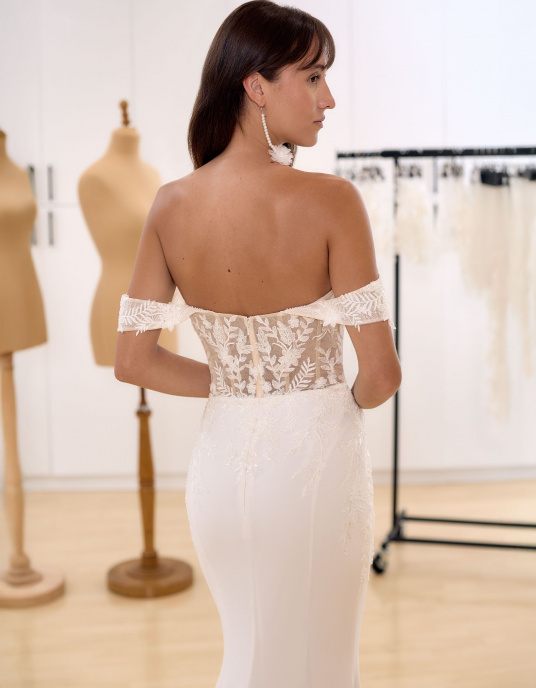 Robes de mariées  Bianco Evento Lali Robe de mariée sirène, sensuelle et parfaitement ajustée, confectionnée en crêpe et dentelle de qualité supérieure. Elle présente une délicate broderie florale en dentelle, un dos droit rehaussé d’un décolleté en cœur, ainsi que des manches tombantes 