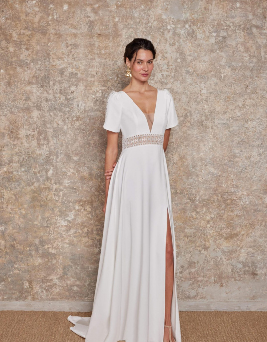 Robes de mariées  Lambert Creation Lys Allure chic et couture pour cette robe originale avec ses manches courtes incrustées de guipure sa ceinture en transparence et son dos bordé de guipure. 