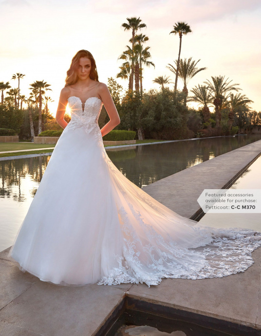 Robes de mariées  Pronovias RINNES Robe de mariée somptueuse au style princier. Le corsage sans manches, avec un décolleté en V, épouse parfaitement le corps, se prolongeant harmonieusement dans une jupe en A, ornée d'une surjupe en dentelle transparente et d'une traîne festonnée gl 