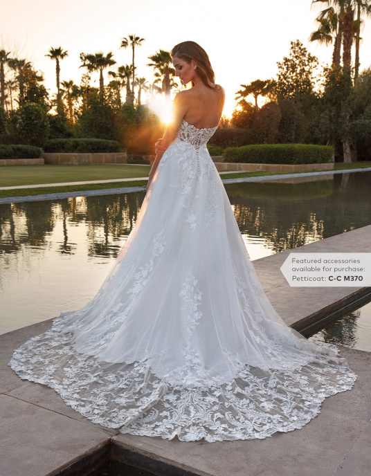 Robes de mariées  Pronovias RINNES Robe de mariée somptueuse au style princier. Le corsage sans manches, avec un décolleté en V, épouse parfaitement le corps, se prolongeant harmonieusement dans une jupe en A, ornée d'une surjupe en dentelle transparente et d'une traîne festonnée gl 