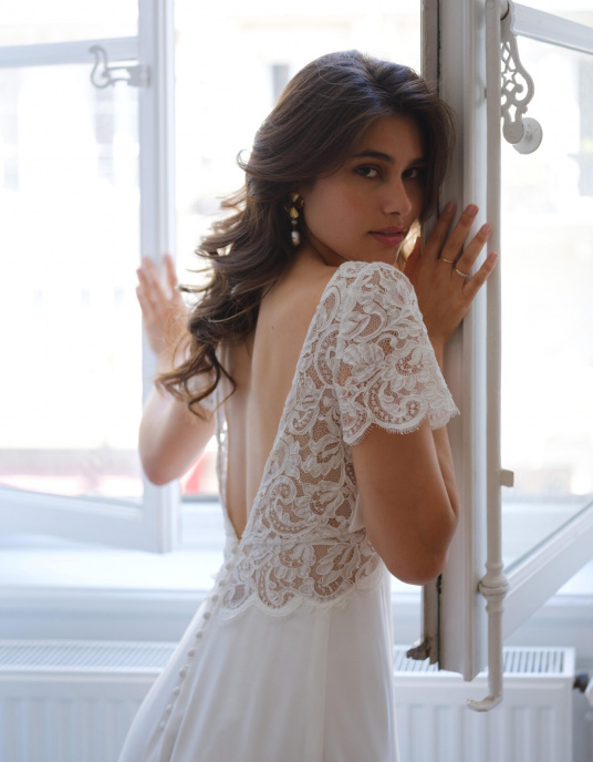 Robes de mariées  Lambert Creation Saturne Allure intemporelle pour cette robe en crêpe et dentelle, à manches courtes et quille en dentelle. 